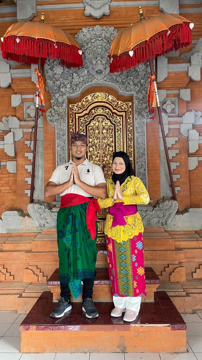 Pasangan honeymoon memakai pakaian tradisional Bali